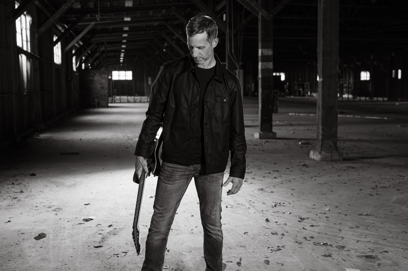 Matthew Hartley standing with a guitar in an empty warehouse — the header image from matthewhartleymusic.com.